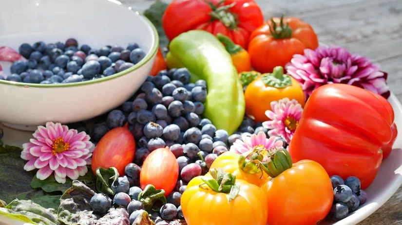 Een schaal vol groente, fruit en bloemen. Een schaal met onder andere tomaten, blauwe bessen en bloemen uit Diana's mooie moestuin.